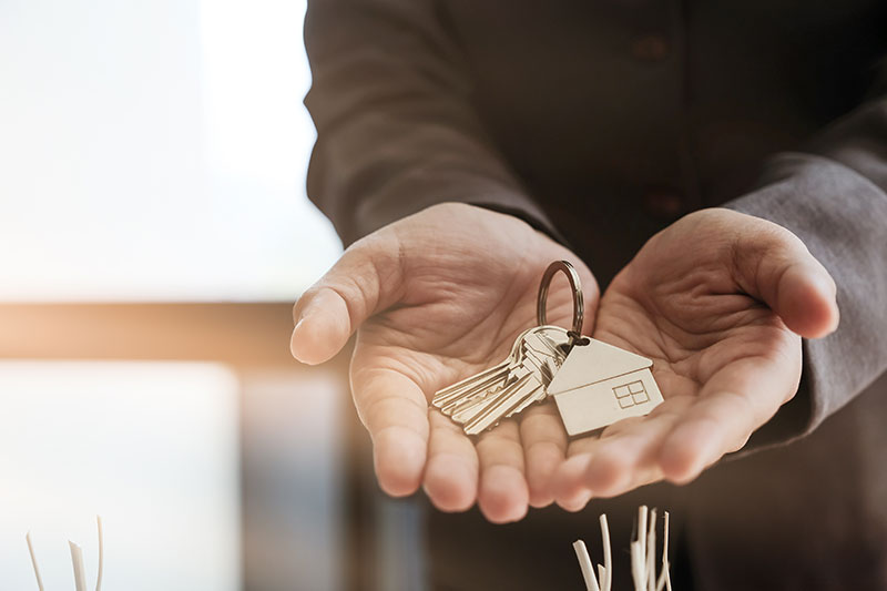 Zwei Hände halten einen silbernen Haustürschlüssel